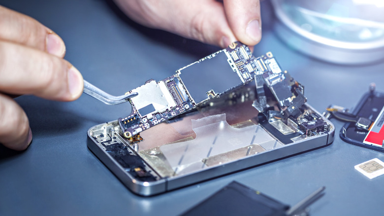 A technician replacing a phone's motherboard