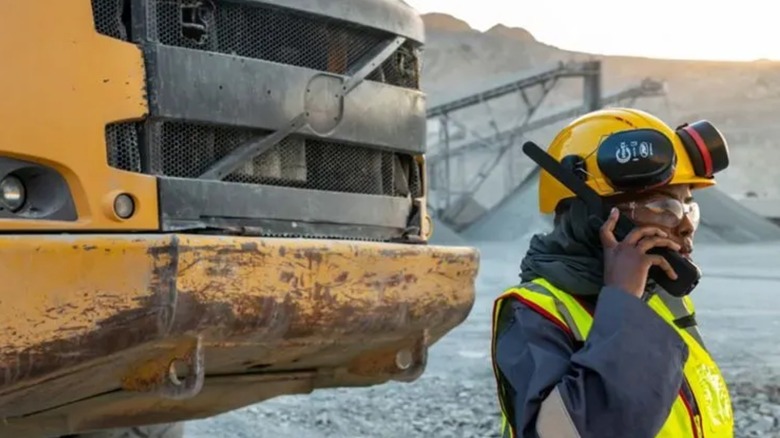 Mine worker in front of truck talking on Inmarsat IsatPhone 2 satellite phone
