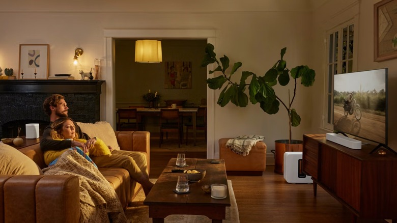 Man and woman on couch watching TV in living room with Sonos surround sound system