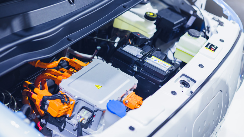 Close up of an EV car engine with the components visible under the hood.