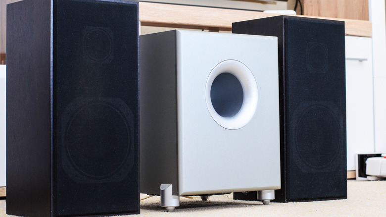 A subwoofer placed between two bookshelf speakers.