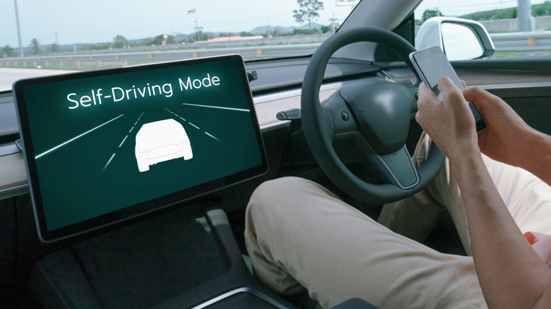 a man on his cell phone while his self-driving car drives itself