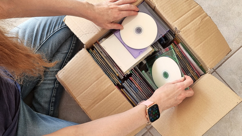 Top-down view of someone looking through old discs stored in a box.