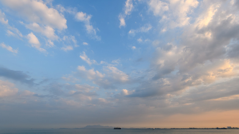 A photo of an overcast sky taken over water with a ship off in the distance