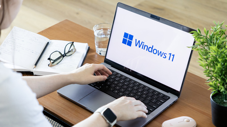 Woman typing on laptop with the Windows 11 logo on screen