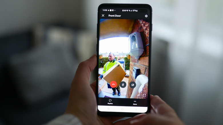 Close-up of smartphone screen showing home security camera footage of delivery person