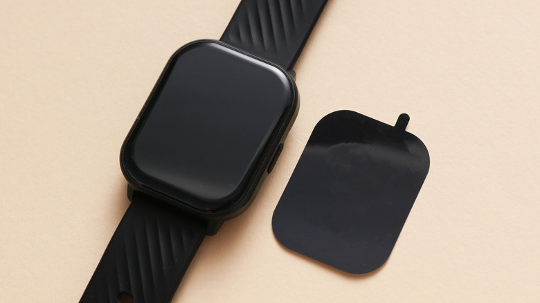 A plastic film screen protector next to a smartwatch.