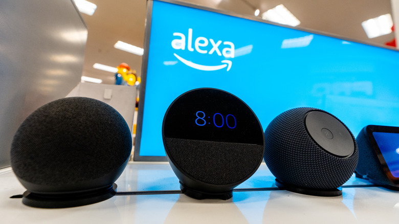 Amazon smart speakers with a screen in the background flashing an Alexa logo.