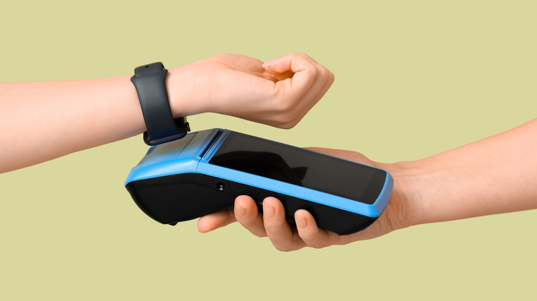 a person's hand paying with their smartwatch
