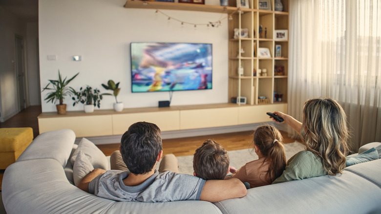 A family of four watching TV in a modern living room.