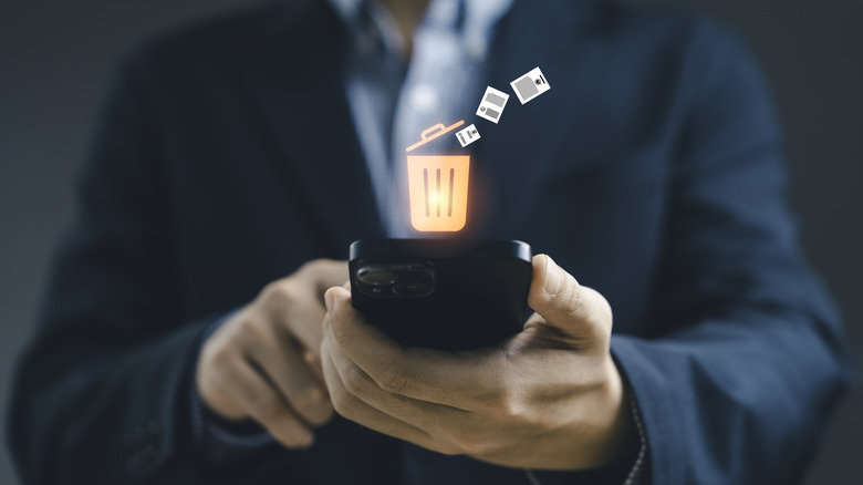 A trash can icon floats above a smartphone.
