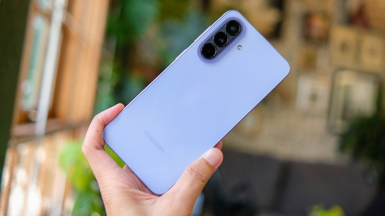A hand holding a Samsung Galaxy A series phone, tilted.