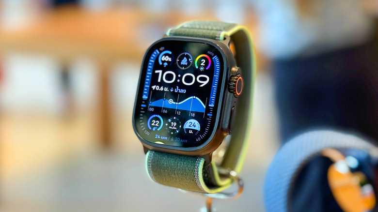 An Apple Watch Ultra with a green band sits on a display seemingly within an Apple Store, though the background is too blurry to confirm
