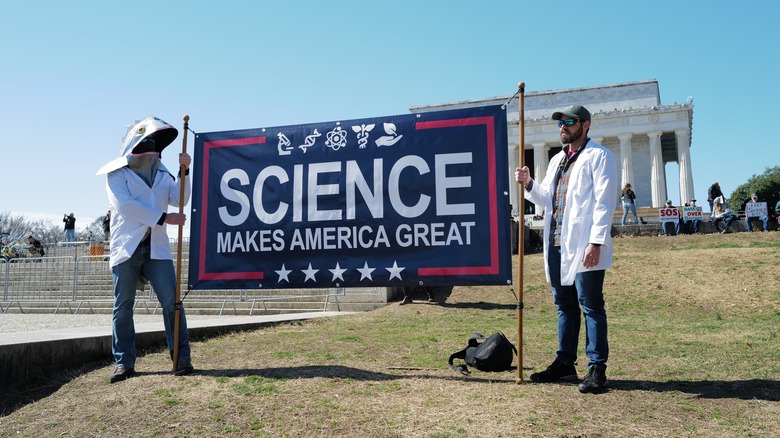 Protestors against the NASA budget cuts hold a sign that says science makes America great