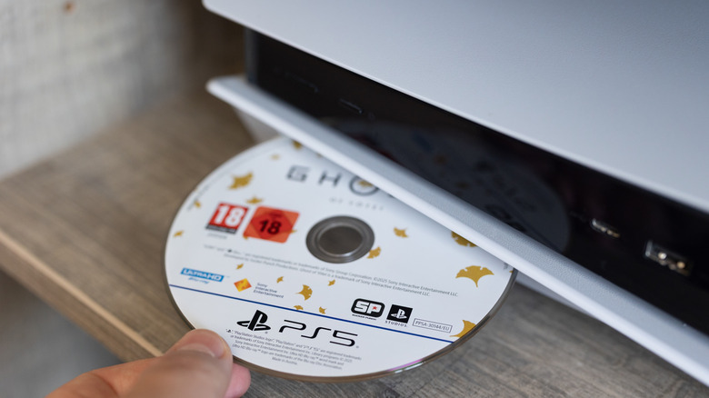 A person inserting the Ghost of Yotei game disc into the PlayStation 5.