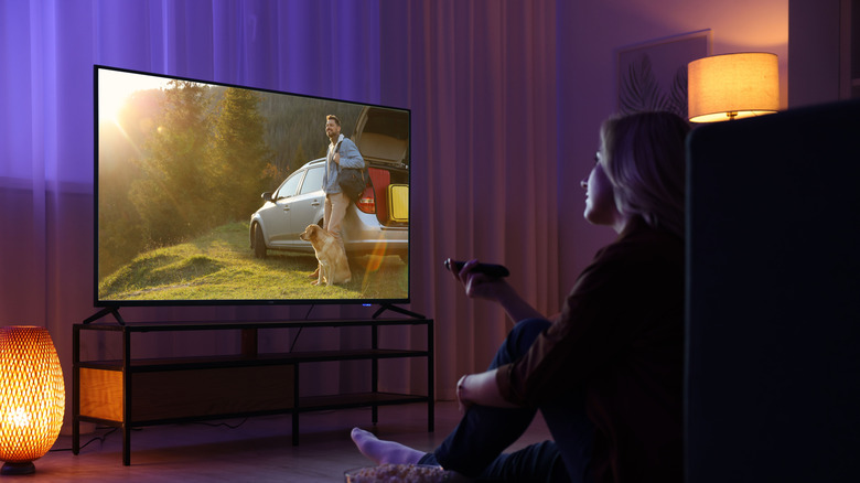 A woman watching TV in a dark living room.