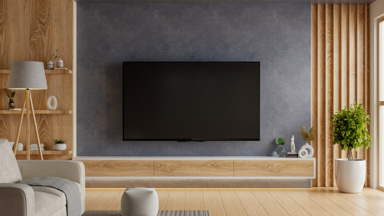 A wall-mounted TV turned off in a modern living room.
