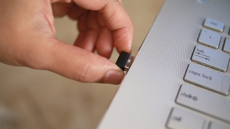 person connecting a USB dongle to a laptop