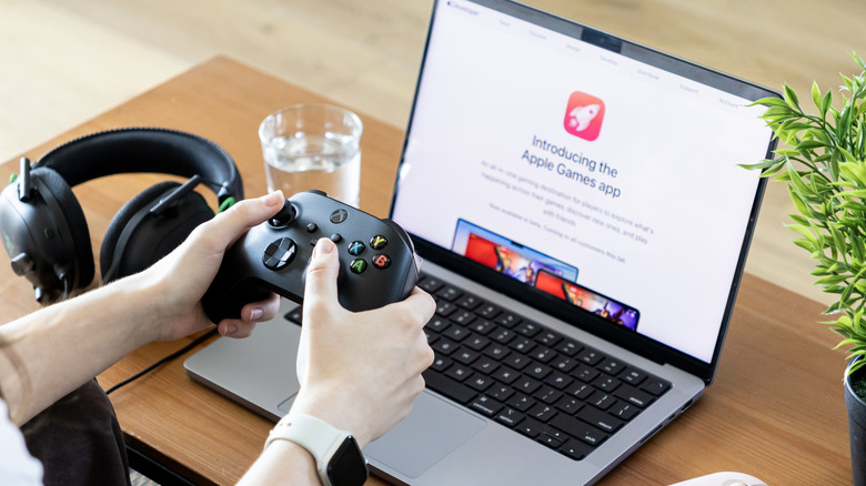 A person gaming with a MacBook and an Xbox controller
