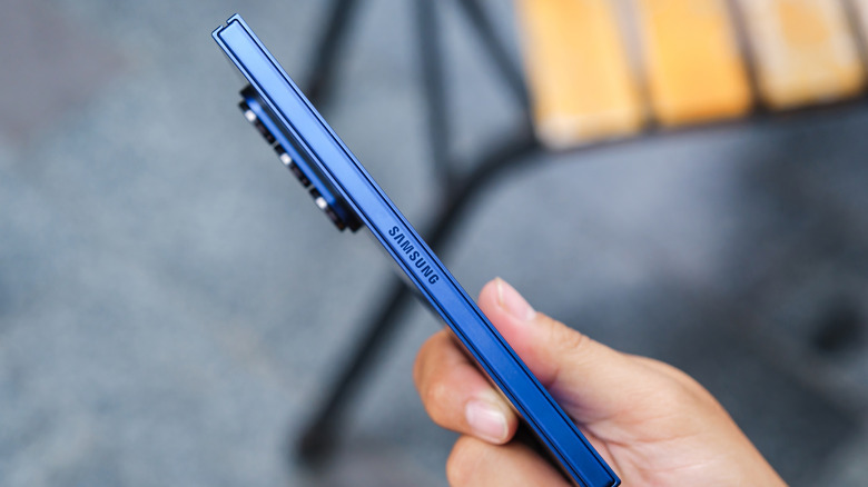 Side view of a blue Samsung phone with Samsung written on its edge and a very big camera bump on its back