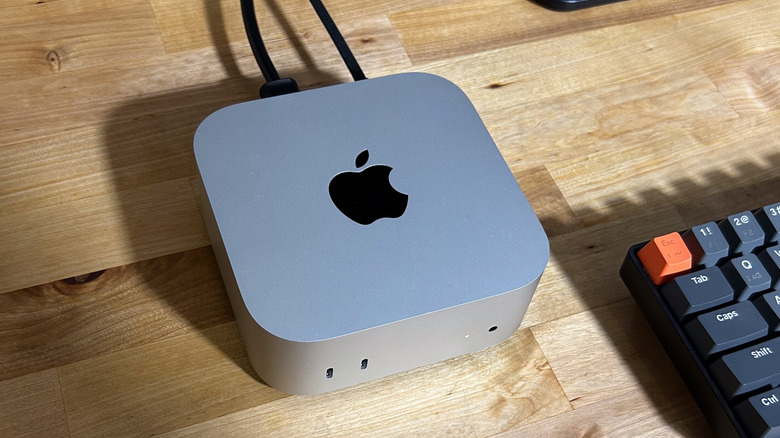 Apple Mac Mini M4 computer on a wooden desk with a keyboard.