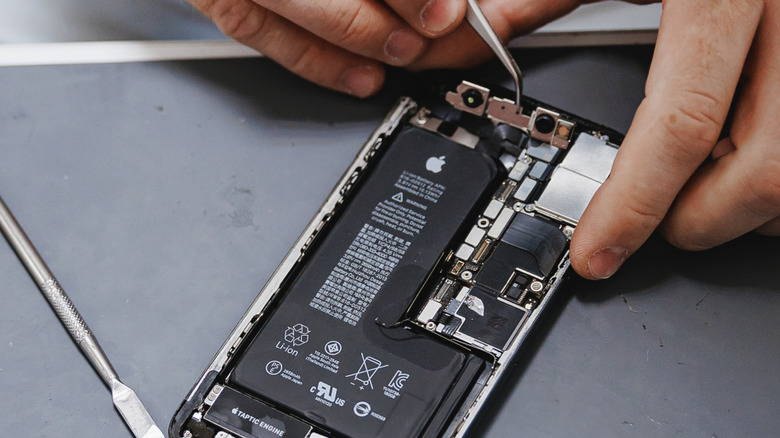 person repairing an iPhone with specialized tools