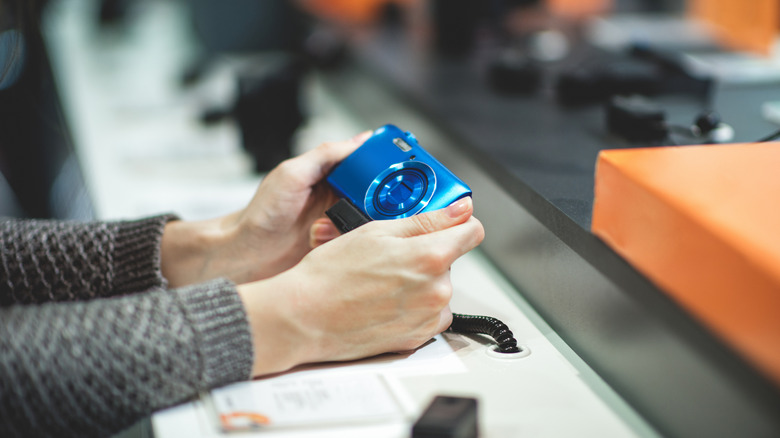 A person looking at a cheap digital camera in a store.