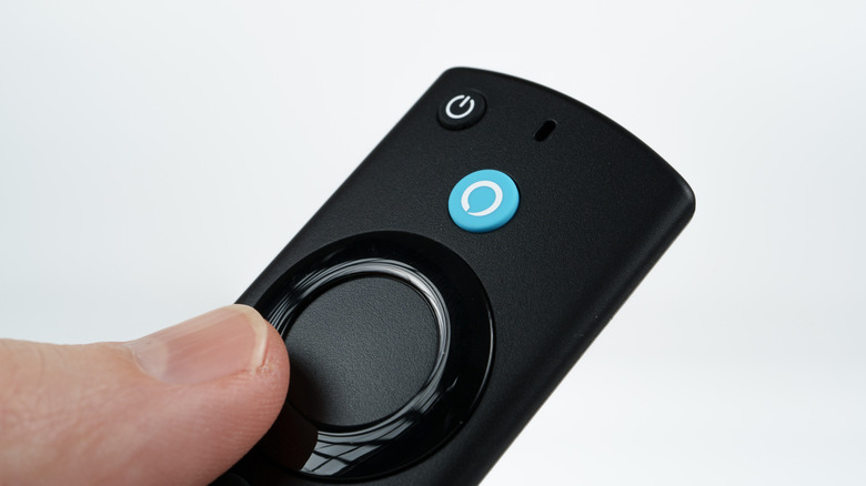 A hand holding a Fire TV remote with Voice Control, both the hand and device are against a white backdrop