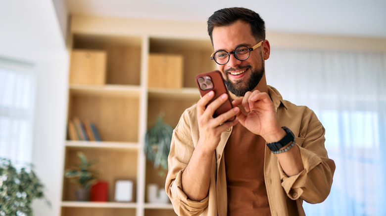 Happy man using smartphone at home