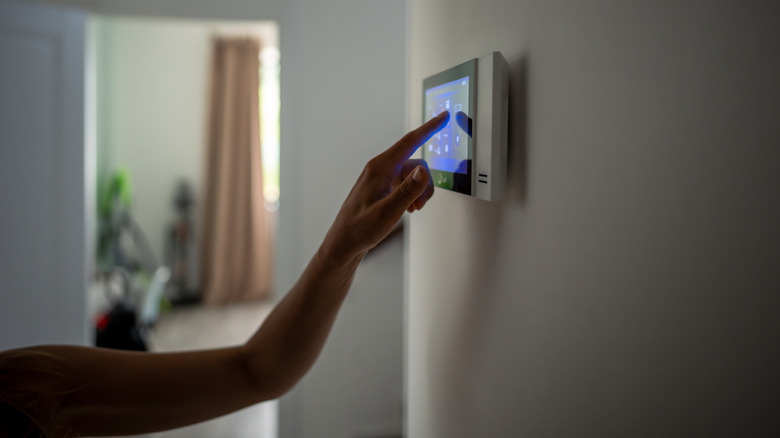 Person adjusting settings on a wall-mounted smart home control panel