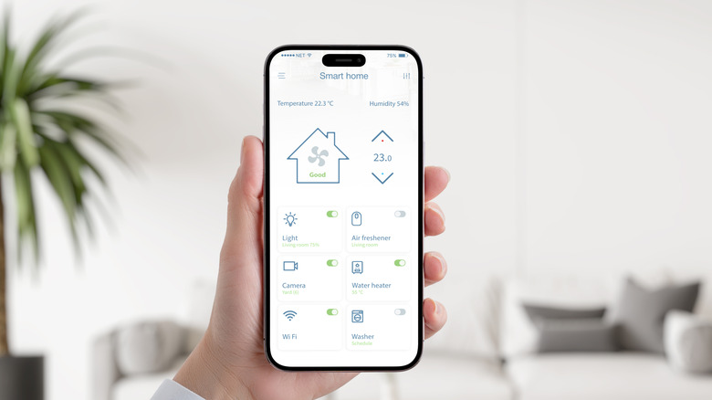 Hand holding a smartphone displaying a smart home control app