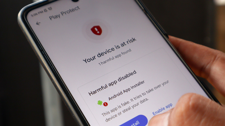 person holding an Android smartphoen with play protect warning about an harmul app