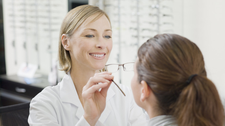 A woman putting glasses on another person