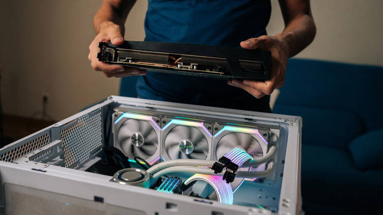 Someone building a custom PC with a nondescript graphics card in hand.