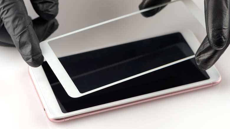 A person installing a screen protector on a smartphone