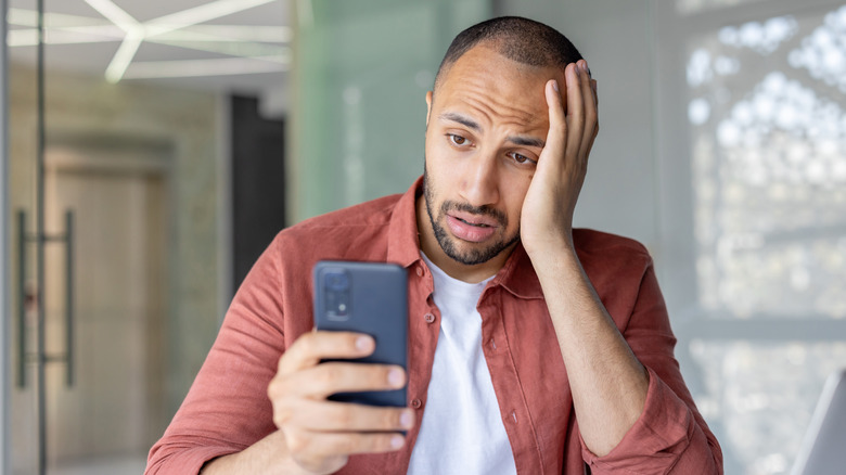 A frustrated man looks at his phone