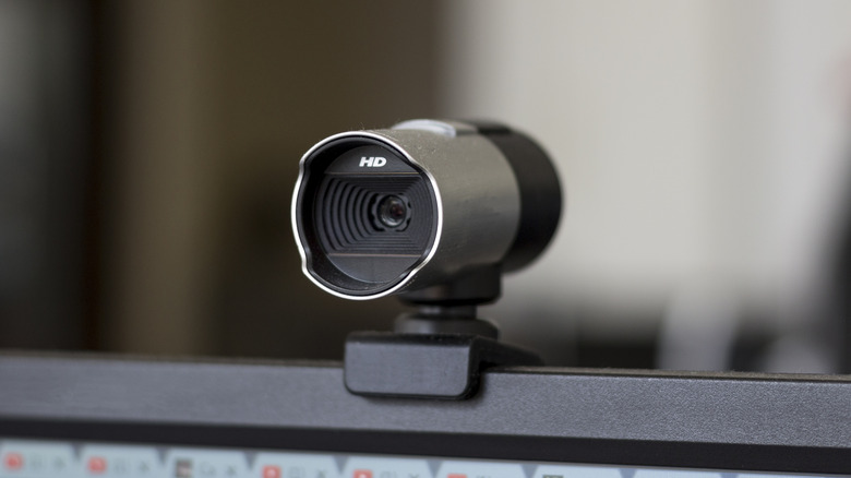 A silver and black HD webcam mounted on top of a monitor
