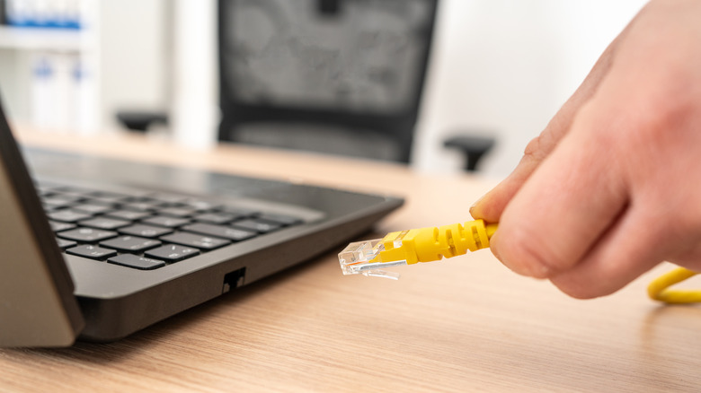 Person plugging an Ethernet cable to a laptop