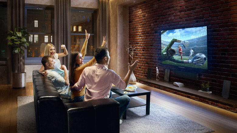 People watching soccer on a TV from the couch.