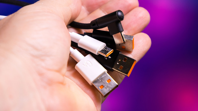 An image of a hand holding various USB cables