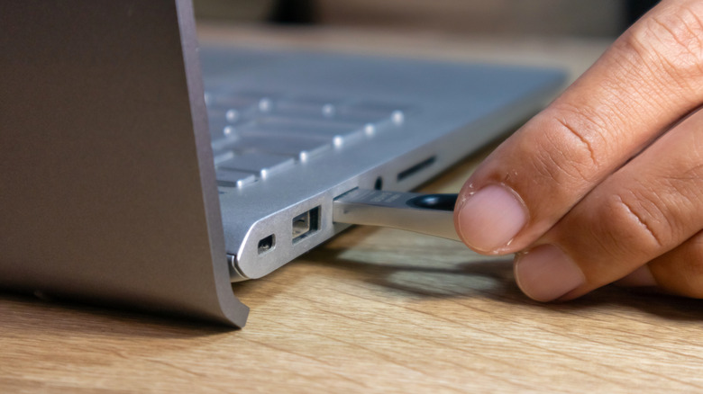 Person connecting a USB flash drive to a laptop