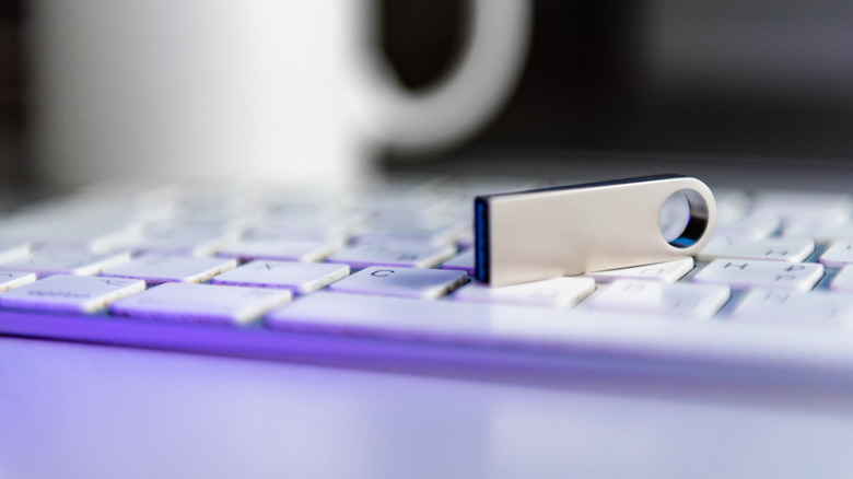 silver flash drive placed on a white keyboard