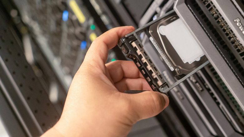 Person adding a hard drive to a server rack