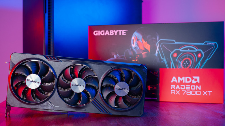 A Gigabyte AMD Radron RX 7800 XT AMD graphics card on a desk with its box and a PC in the background