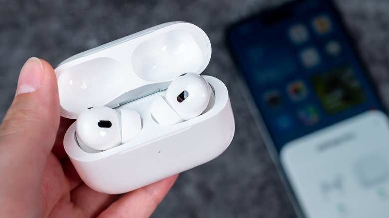 A person holding an open AirPods Pro charging case with both earbuds placed inside.