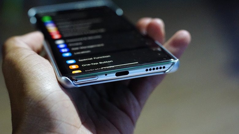 Hand holding an Android smartphone, angled to show the USB-C port on the bottom of the phone.