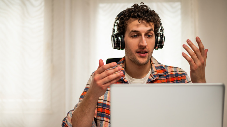 person wearing wireless Bluetooth headphones during a video call on a laptop