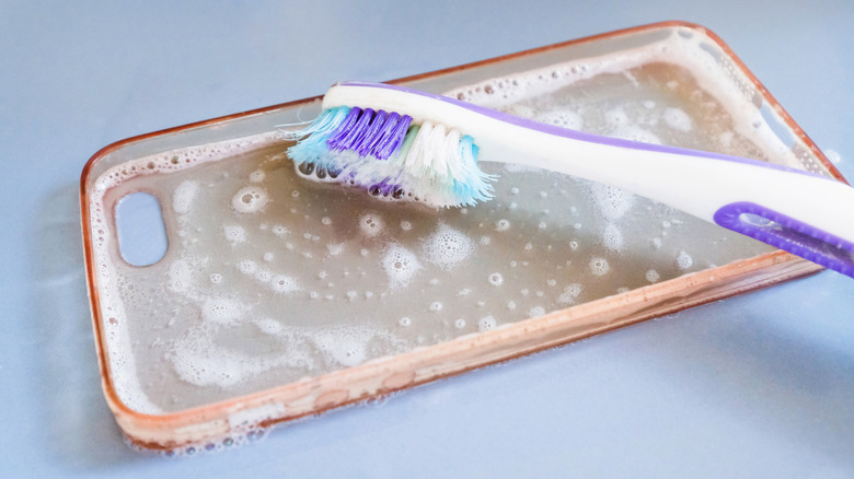 A cellphone case that is being washed with a toothbrush