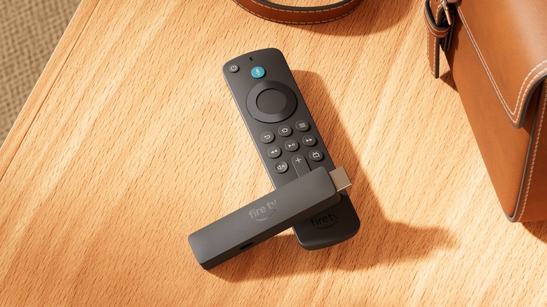 A Fire TV Stick model on a wooden desk next to a leather bag