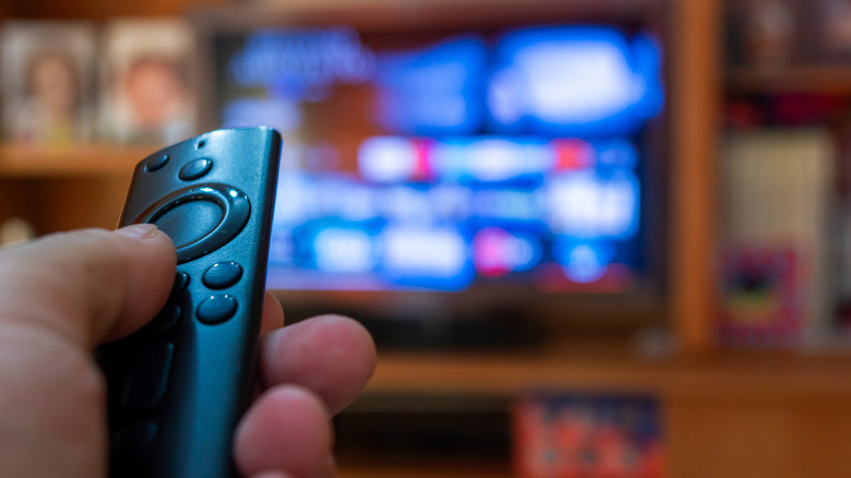 Close-up of a person holding the Alexa Voice Remote with a blurred TV In the background
